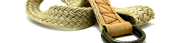 A woven natural fiber belt with a leather end and a metal loop, artistically coiled.