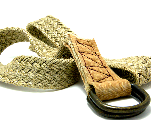 A woven natural fiber belt with a leather end and a metal loop, artistically coiled.